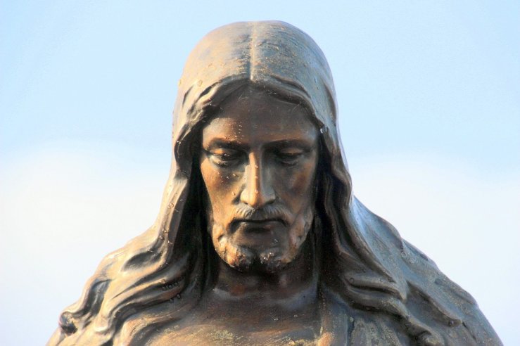A statue of Jesus with His face looking downward. His mouth is closed and he seems contemplative.