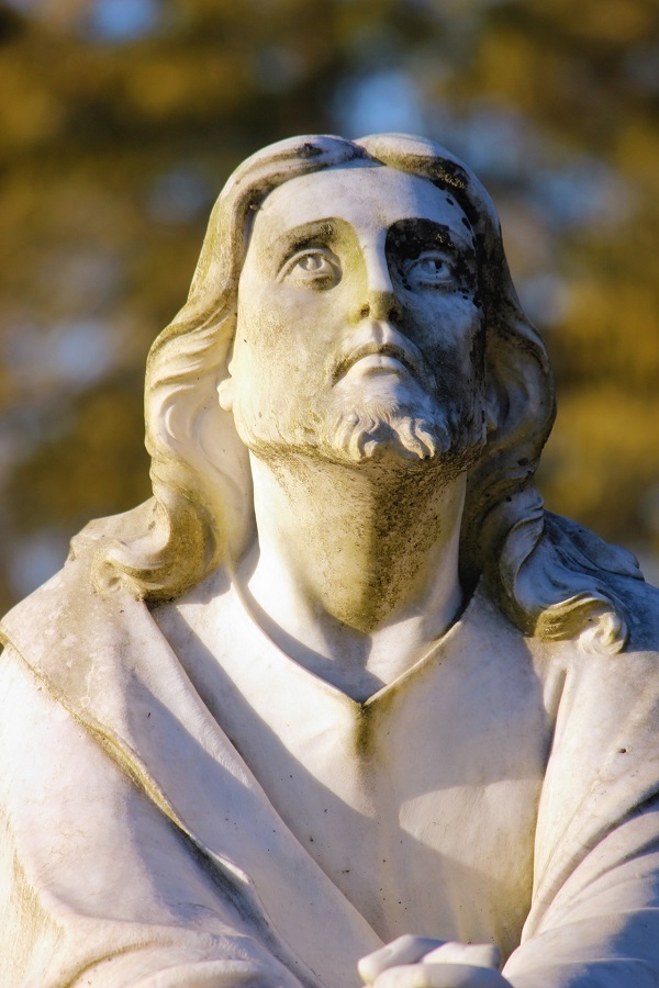 A statue of Jesus looking upward to the heavens and His hands together. He is wearing His typical garb.