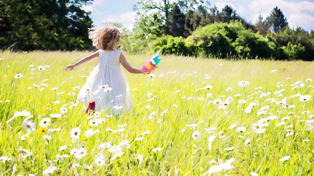 A little girl running through a field of daisies on a bright Summer day.