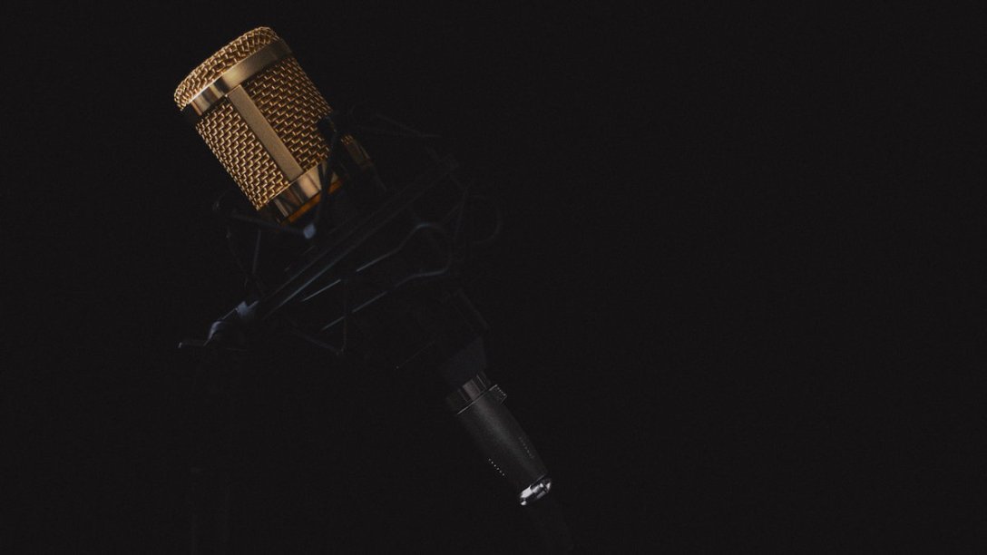 A microphone on a stand with a black background.